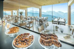 a table with two cakes and tables with mountains in the background at Hotel Belalp in Belalp