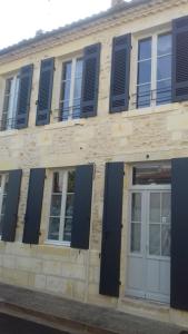 un bâtiment avec des fenêtres à volets bleus et une porte dans l'établissement Arc en ciel, à Lesparre-Médoc