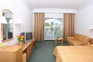 Habitación de hotel con cama y TV en El Mouradi Skanes en Monastir