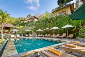 a pool at a resort with chairs and umbrellas at Lembongan Cliff Villas in Nusa Lembongan