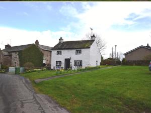 a white house on the side of a grass field at White Cottage Askham in Askham