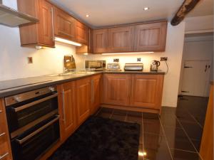 a kitchen with wooden cabinets and a counter top at White Cottage Askham in Askham