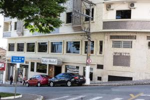 Un edificio con dos coches aparcados delante. en Kafé Hotel, en Guaratinguetá