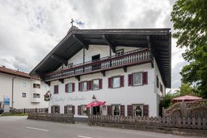 a large white building with red shuttered windows at Landgasthof Oberlander in Kirchbichl