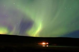 una aurora sobre una carretera con un coche debajo en Langavatn Guesthouse, en Aðaldalur