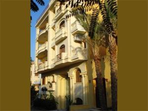 a tall building with a palm tree in front of it at Bahga Palace 3 Residential Apartments in Hurghada