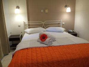 a bed with towels and a red flower on it at Sunny Studios in Svoronata