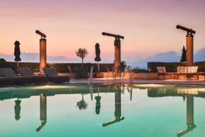 a swimming pool with a sunset in the background at Royal Hotel Thessaloniki in Perea