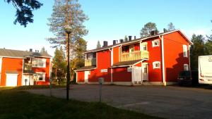 un gran edificio naranja con una furgoneta estacionada al lado en Apartments Rautulampi, en Saariselkä
