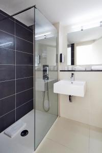 ein Bad mit einer Dusche und einem Waschbecken in der Unterkunft Kyriad Hotel Meaux in Meaux