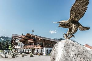 Una statua di un'aquila su una roccia di fronte a un edificio di Hotel Riedl a Kössen