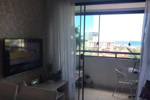 a living room with a television and a view of the ocean at Apartamento 2 Quartos vista mar in Salvador