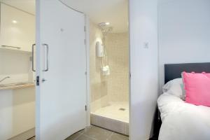 a bedroom with a shower and a bed with a pink pillow at Artist Studio - By My Getaways in Brighton & Hove