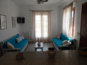 a living room with blue couches and a table at Glyfada Beach Studios in Kastraki