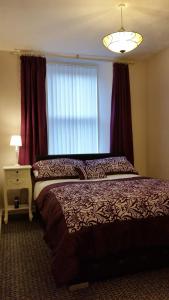 a bedroom with a bed and a window with red curtains at Central Dumfries in Dumfries