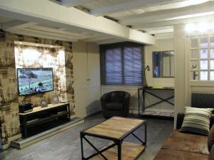 a living room with a tv and a couch and a table at Honfleur de lys in Honfleur