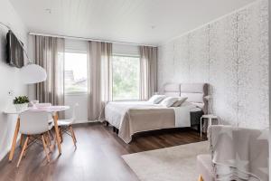 a white bedroom with a bed and a table and chairs at Apartment Kievarinhovi in Kempele