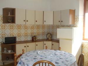 a kitchen with a table and a refrigerator at Villa Spaia in Brancaleone Marina +12 photos