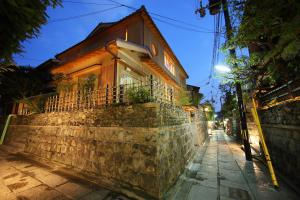 a house on a stone wall on a street at night at Small Luxury Ryugin in Kyoto