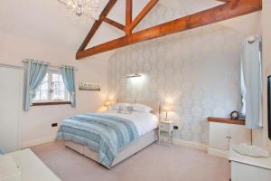 ヨークにあるCity Apartments - Holtby Grange Cottagesの白いベッドと木製の天井が備わるベッドルーム1室が備わります。