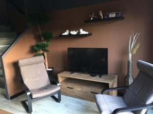 ein Wohnzimmer mit 2 Stühlen und einem Flachbild-TV in der Unterkunft Ameland Rentals Hollum in Hollum