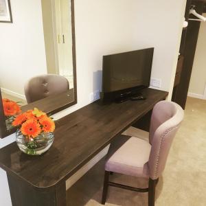 a desk with a television and a vase of flowers at Cohannon Inn in Dungannon