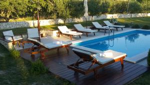 eine Gruppe von Stühlen und Tischen neben einem Pool in der Unterkunft Luxury Villa Luminosa in Split