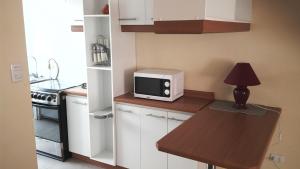 a kitchen with a microwave and a table with a lamp at Casas Amobladas y Equipadas Calama in Calama