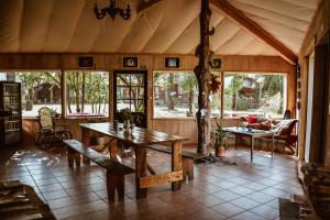 a living room with a wooden table and chairs at Sunny Nights Homestead Rustic House in Gataučiai