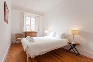 una camera bianca con un grande letto bianco e una finestra di Central, Charming, Quiet, Garden and Parking a Lisbona