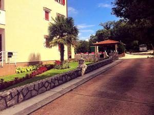 a street next to a building with a palm tree and flowers at Apartments Hanka in Njivice