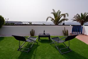 a patio with a table and chairs on the grass at Villa Vista Mar in Playa Blanca