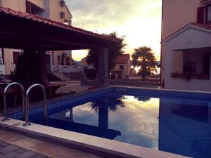 a swimming pool next to a building with a reflection in the water at Apartments Hanka in Njivice