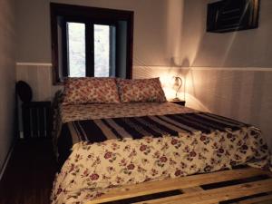 a bedroom with a bed with a floral comforter and a window at Torremochada in Cáceres