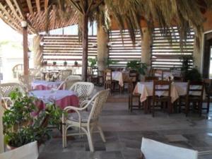 a restaurant with tables and chairs and tablesearcher at Santa Barbara Lakis Apartments in Perivólion