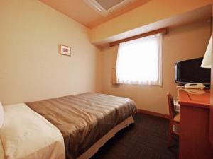 een hotelkamer met een bed, een bureau en een raam bij Hotel Route-Inn Aomori Ekimae in Aomori