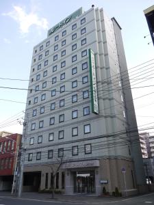 a large white building with a sign on it at Hotel Route-Inn Sapporo Kitayojo in Sapporo