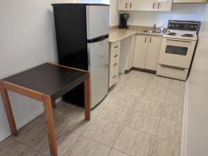 eine Küche mit einem Kühlschrank und einem Tisch darin in der Unterkunft Franklin Motel, Tent & Trailer Park in North Bay