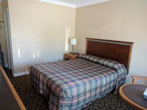 a hotel room with a bed with a plaid blanket at Franklin Motel, Tent & Trailer Park in North Bay +8 photos