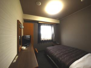 a bedroom with a bed and a desk with a television at Hotel Route-Inn Nakatsugawa Inter in Nakatsugawa