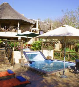 a resort with a swimming pool with an umbrella at Crocodile Kruger Safari Lodge in Marloth Park