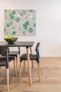 uma mesa de jantar e cadeiras com um quadro na parede em Caroline Serviced Apartments Sandringham em Sandringham