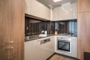 una cocina con armarios blancos y fregadero en Caroline Serviced Apartments Sandringham, en Sandringham