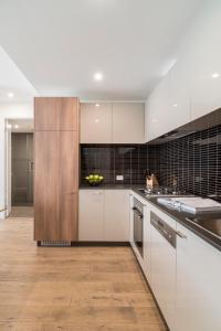 uma cozinha com armários brancos e piso em madeira em Caroline Serviced Apartments Sandringham em Sandringham