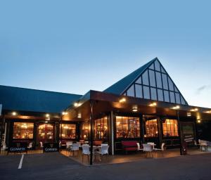 a building with tables and chairs in front of it at Arthur's Court Motor Lodge in Christchurch