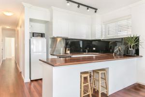 La cuisine est équipée de placards blancs et d'un réfrigérateur blanc. dans l'établissement Beachfront on Golden Mile, à Sydney