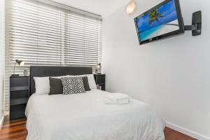 een slaapkamer met een bed en een tv aan de muur bij Beachfront on Golden Mile in Sydney
