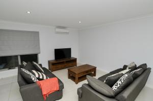a living room with two couches and a tv at Doze On Green in Wangaratta