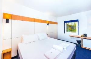 a bedroom with a large white bed and a desk at Ibis Budget - Casula Liverpool in Liverpool