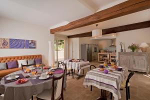 a dining room with tables and chairs and a kitchen at Les Couleurs du Verger in Beaumont-les-Autels